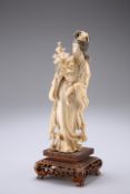 A CHINESE IVORY FIGURE, CIRCA 1900, carved in flowing robes and holding a rose, on a carved wooden