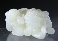 A CHINESE JADE CARVING, depicting a seated shishi with young. 3.5cm by 6cm.