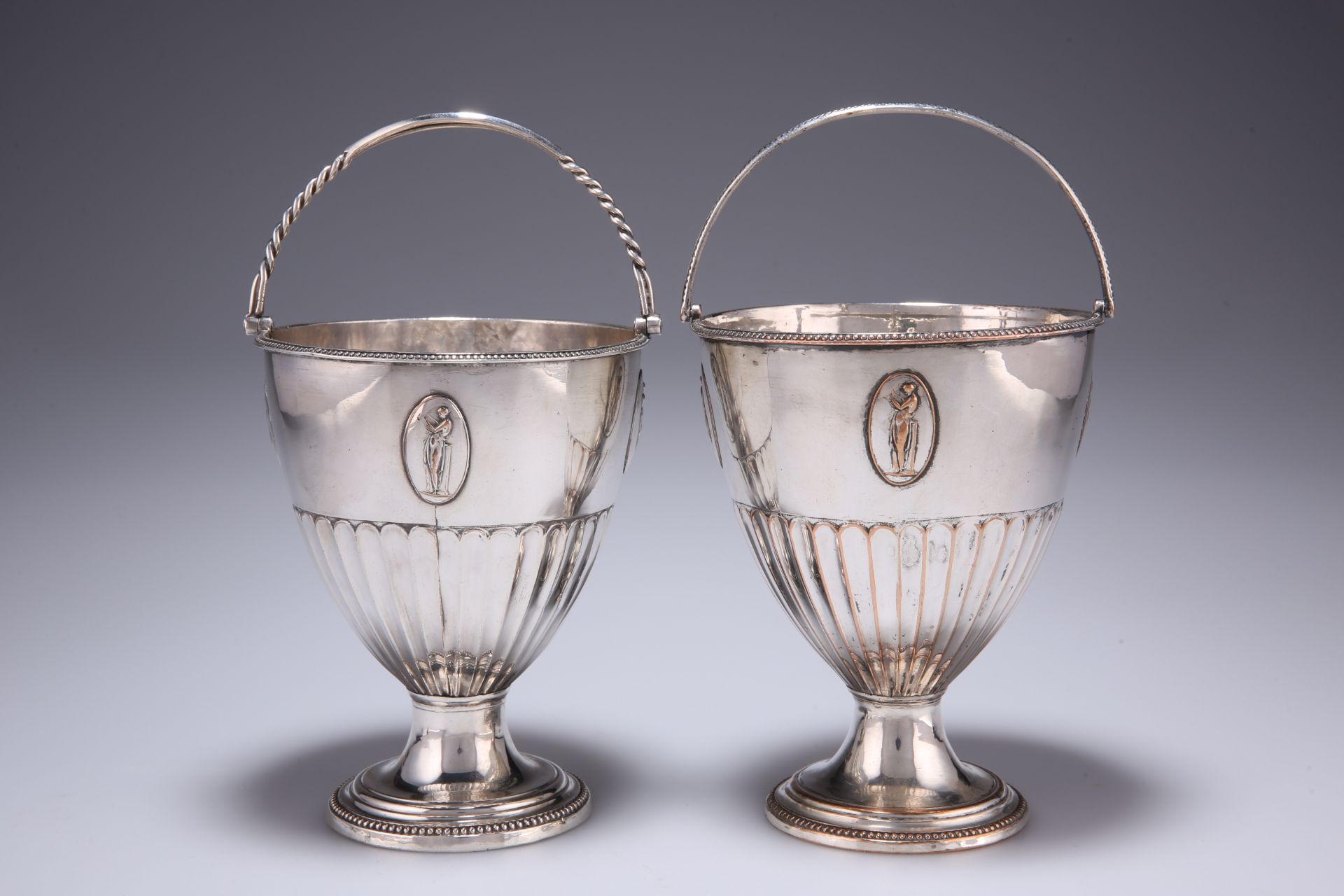 TWO GEORGIAN SILVER-PLATED PEDESTAL BASKETS, each bowl of fluted trumpet form with four applied