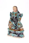 A CHINESE SANCAI GLAZED FIGURE OF A GUARDIAN, LATE MING DYNASTY, modelled seated, decorated in
