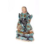 A CHINESE SANCAI GLAZED FIGURE OF A GUARDIAN, LATE MING DYNASTY, modelled seated, decorated in