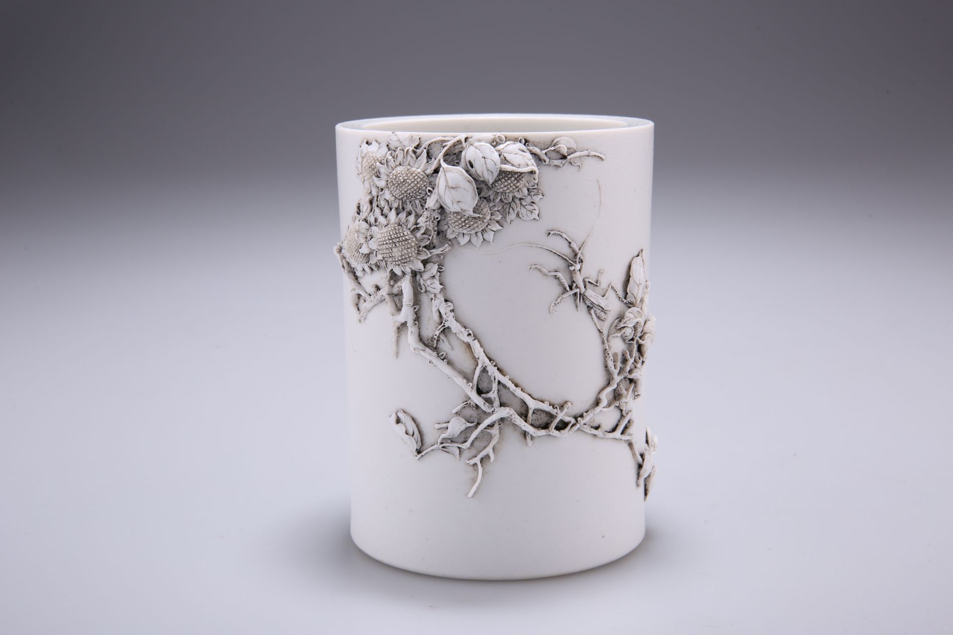 A CHINESE BLANC DE CHINE BRUSH POT, cylindrical, decorated in relief with an insect amidst