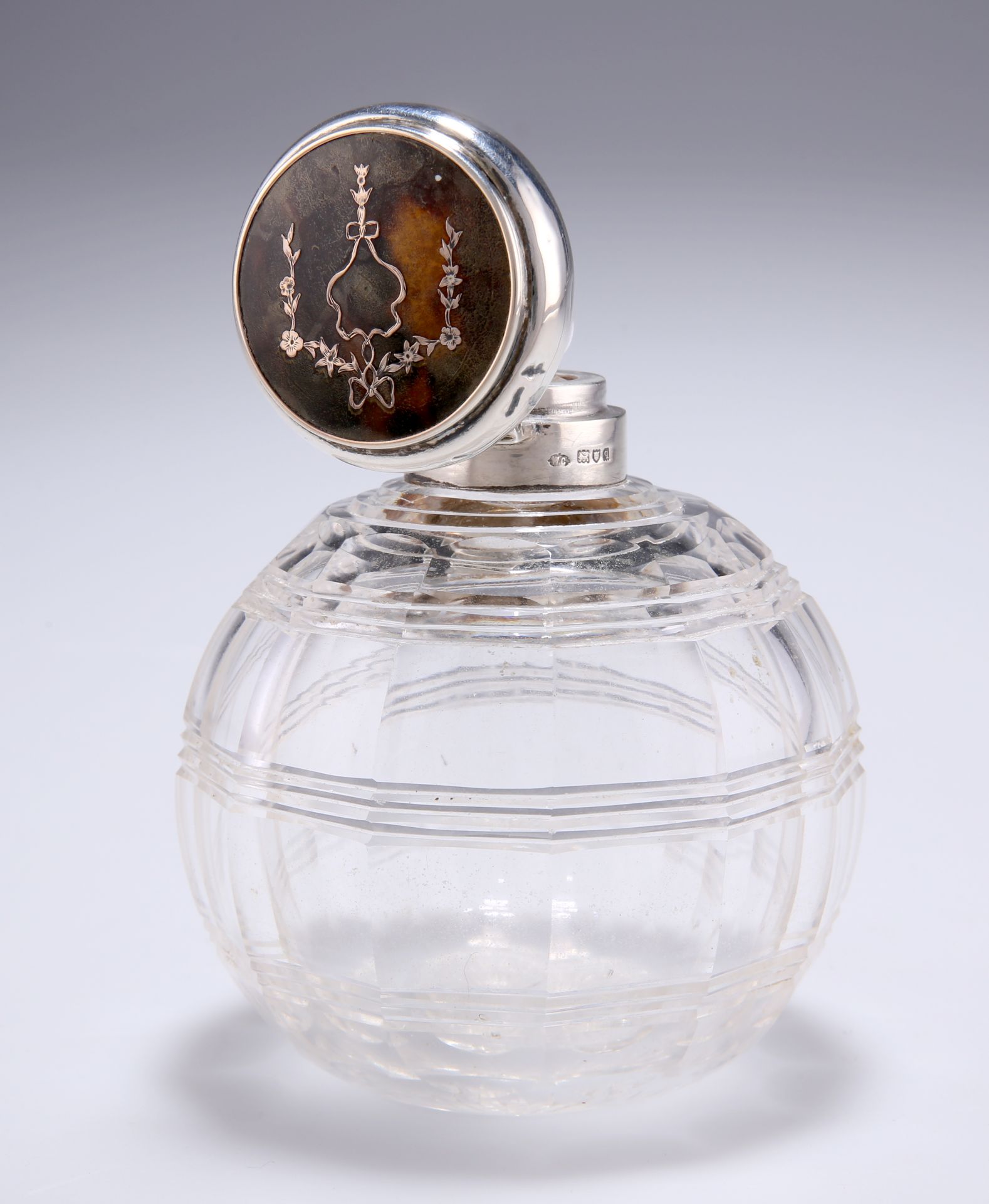 A GEORGE V SILVER AND TORTOISESHELL TOPPED CUT-GLASS SCENT BOTTLE, by William Comyns & Sons,