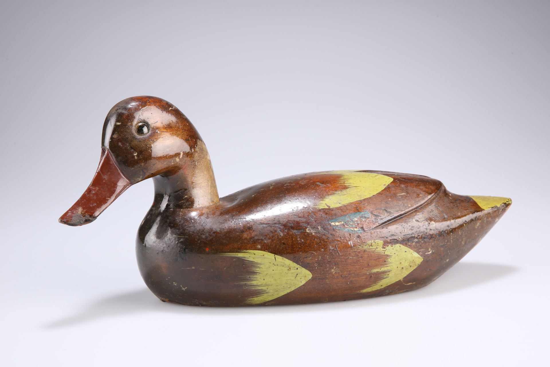 A VICTORIAN CARVED AND PAINTED DUCK DECOY with inset glass eyes. 35cm long