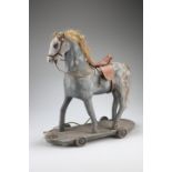 A VICTORIAN PAINTED PAPIER MACHE PULL ALONG HORSE, with leather saddle and bridle. 44cm highThe