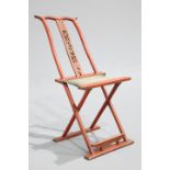 A CHINESE RED LACQUERED FOLDING CHAIR, with footrest and original fabric, central splat carved