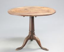 A GEORGE III OAK TILT-TOP TRIPOD TABLE, the circular top raised on a gun-barrel stem continuing to