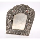 A TIBETAN WHITE-METAL PICTURE FRAME, decorated with figures, easel backed. 11.5cm highThe absence of