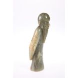 A CHINESE JADE FIGURE, carved as a scholar, standing with arms around his back. 13.5cm high
