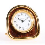 A CARTIER YELLOW-METAL STRUT CLOCK, the arch-top case housing a circular white dial, signed 'Cartier