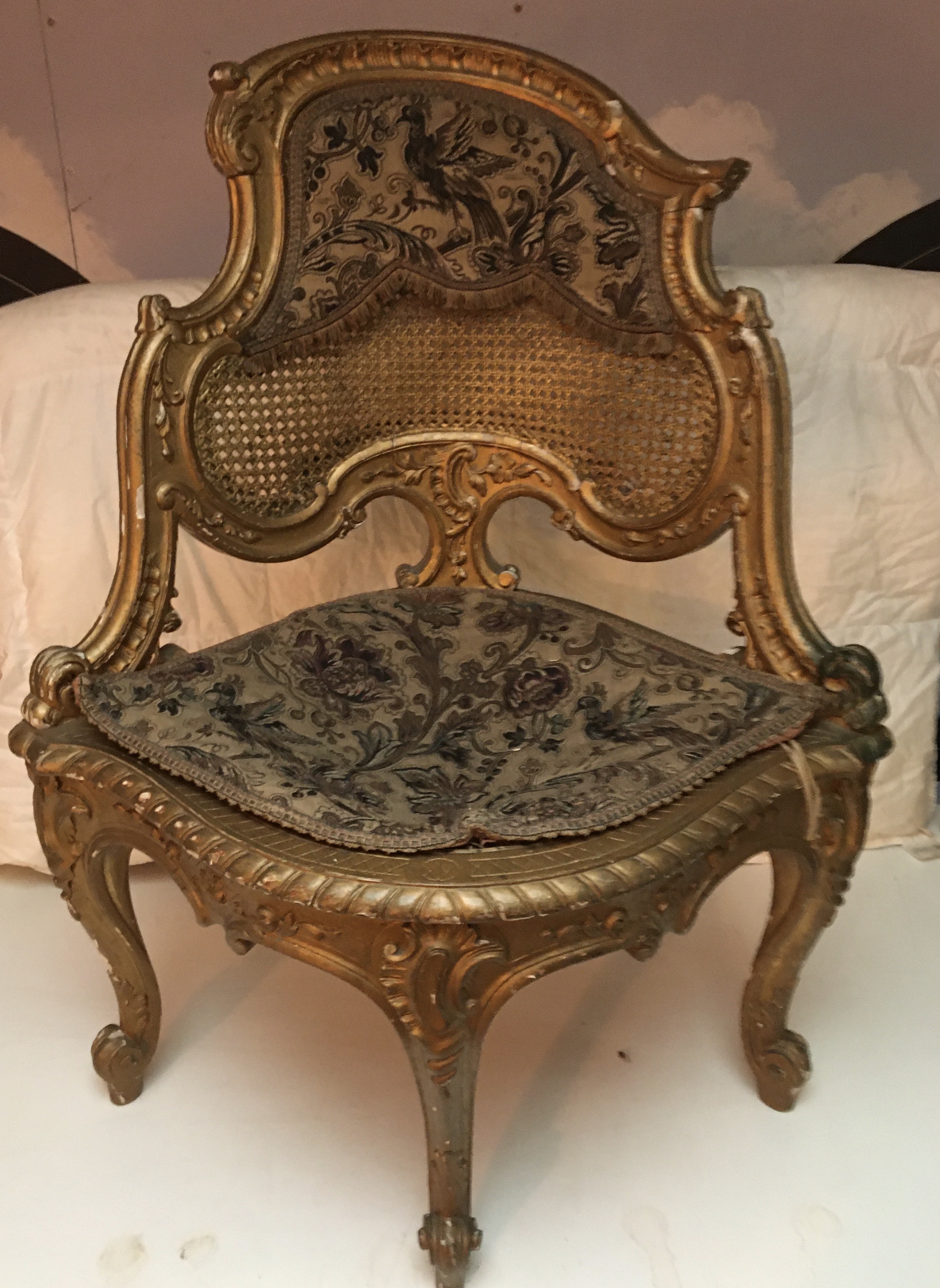 Ornate gilt embroidered rattan backed corner seat.