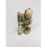 Meiji period marine ivory carving of a kneeling man with bag.