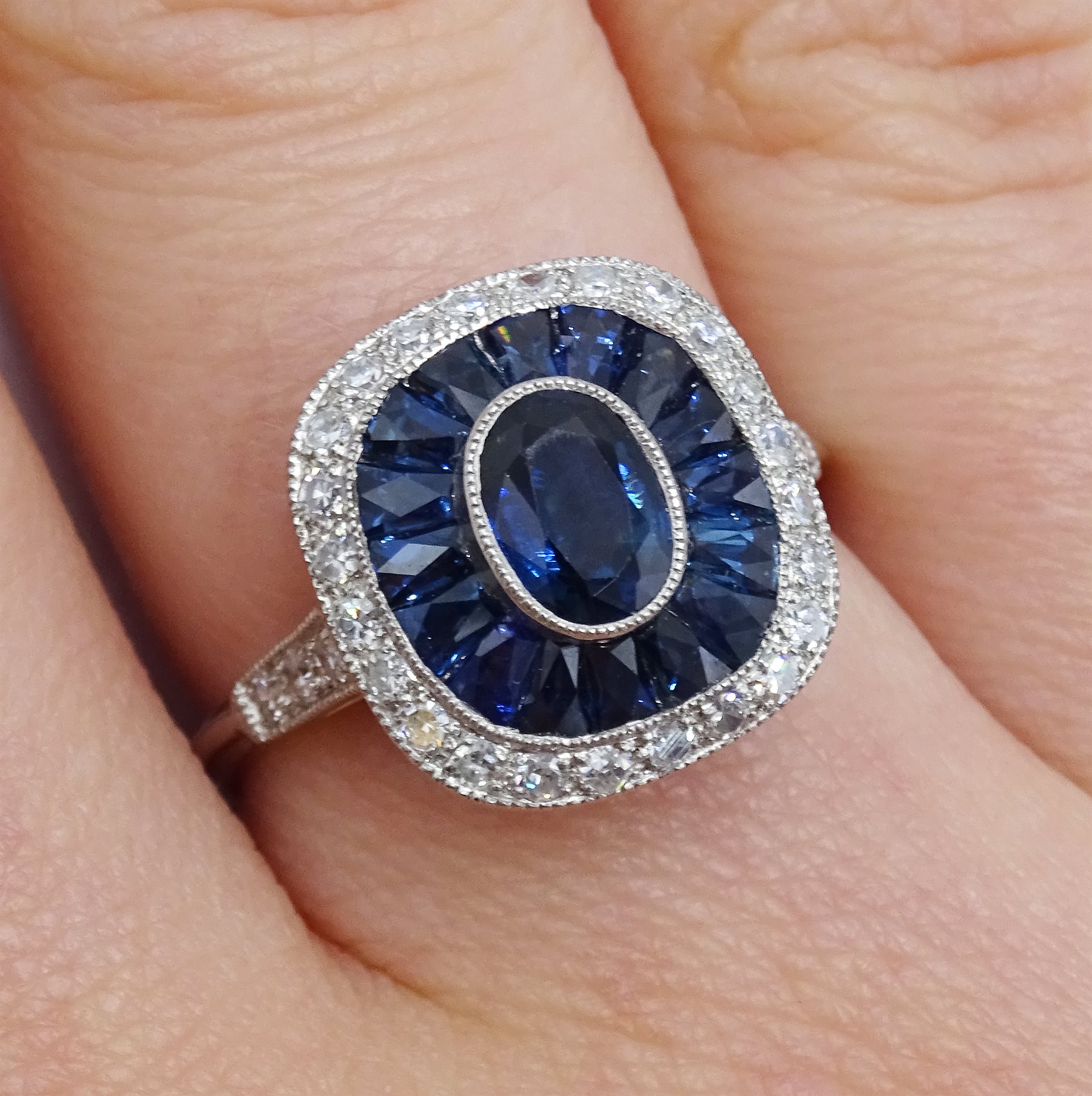 Platinum sapphire and diamond ring, the central oval sapphire surrounded by halo of calibre cut - Image 2 of 5