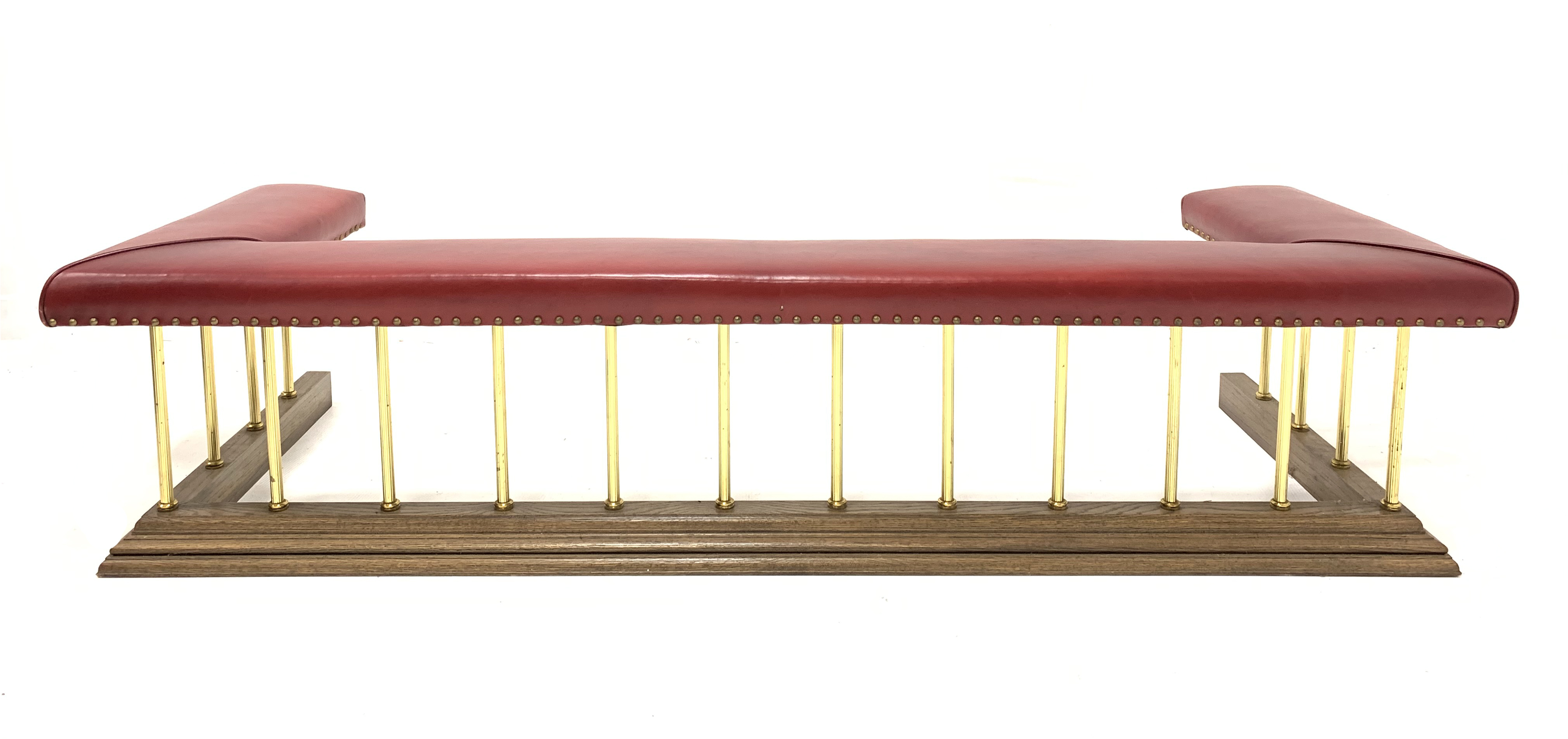 Late 20th century club fender, red studded faux leather upholstered seat raised on reeded brass