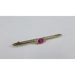 Early 20th century gold and platinum bar brooch, collet set with a cushion cut ruby flanked by