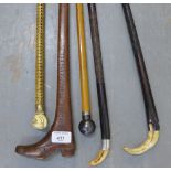 A collection of five walking canes to include an ivory fist handle, a wooden boot handle and
