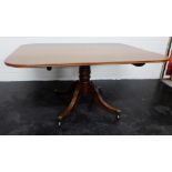 Mahogany tilt top table, on a baluster column base with splayed quadripartite legs 74 x 154cm