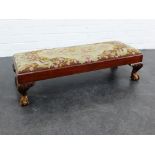 A mahogany framed footstool with tapestry top and raised on claw and ball feet, 26 x 95cm