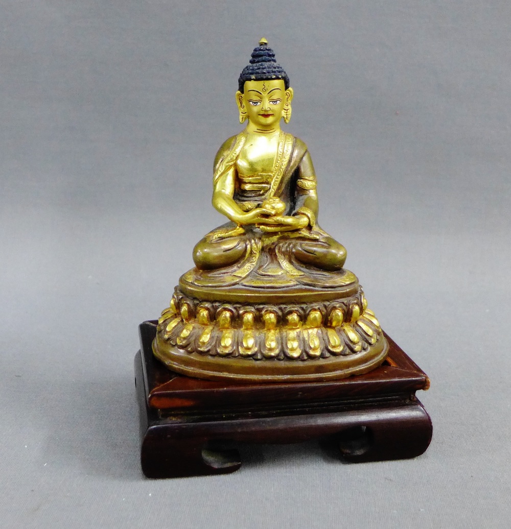 Gilt metal Buddha, typically modelled seated on a lotus base, together with a hardwood stand, 11cm