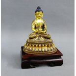 Gilt metal Buddha, typically modelled seated on a lotus base, together with a hardwood stand, 11cm