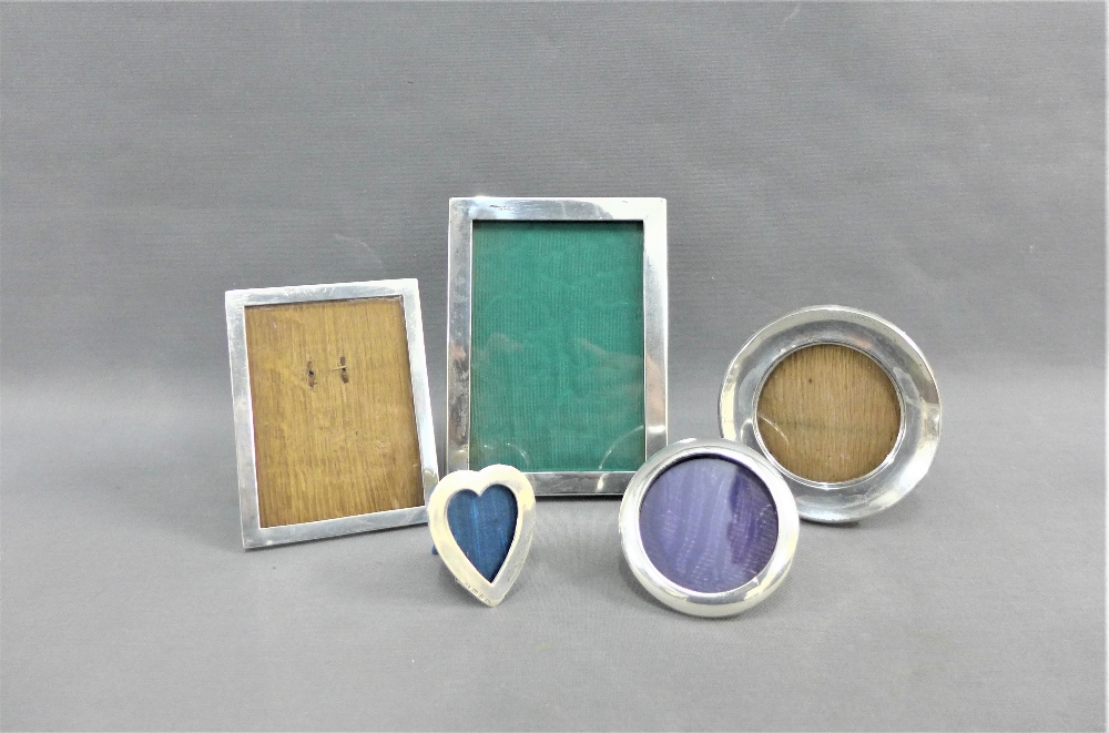 A collection of five silver photograph frames to include two rectangular, two circular and one heart