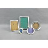 A collection of five silver photograph frames to include two rectangular, two circular and one heart