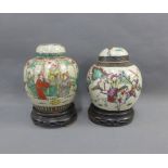 Two Chinese ginger jar and covers painted with Warrior figures with hardwood stands, 17cm high, (2)