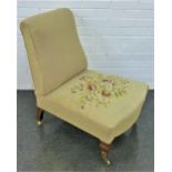 Upholstered nursing chair on mahogany legs with brass castors, 76 x 62cm