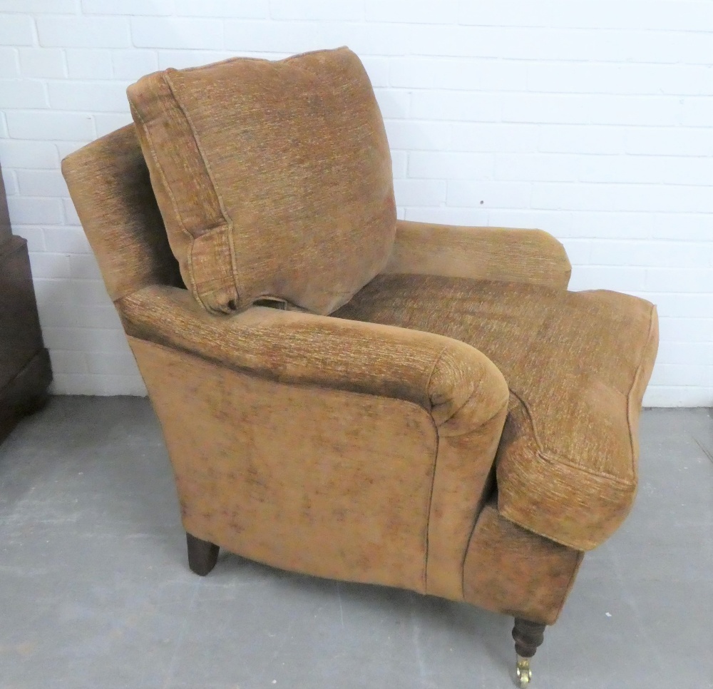 Pair of modern upholstered armchairs, with long cushioned seats, mahogany legs and brass castors,