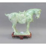 Green hardstone Tang style horse on a shaped wooden base, 21cm high