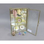 Glass cabinet containing a collection of miniature porcelain plates, a Swarovski crystal sphere,