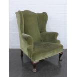 A green upholstered wing back armchair, on mahogany cabriole legs, 110 x 80 x 60cm