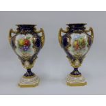 A pair of Royal Worcester vases with gilt twin handles and hand painted fruit panels, signed