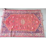 An Eastern hand knotted rug, the red field with animal and bird motifs within flowerhead borders,