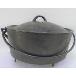 Cast iron cauldron style pot and cover with swing handle and raised on three pointed feet, 40cm