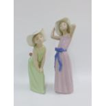 Two Lladro female figures, one wearing a lilac dress the other wearing green, with printed