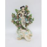 English porcelain figure of a musician, modelled standing on a rococo style base against a floral