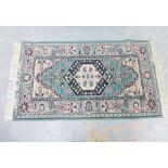Machine made rug with pale green field, 145 x 81cm