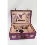 Early 20th century purple suede vanity case containing a part suite of silver and enamel