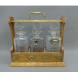 Oak Tantalus with three various decanters and stoppers, two decanter labels to include Hollands