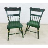 Pair of green painted wooden side chairs with floral patterned top rail, spindle backs and solid