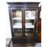 Mahogany display cabinet, the carved cornice top over a pair of glazed doors with a shelved interior