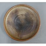 Studio pottery charger by Angus Macleod with a brown glaze and signed with monograms, 40cm diameter