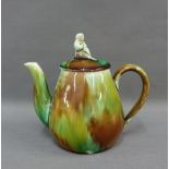 Small Scottish pottery teapot with a brown and green streaked glaze, the cover with a figural