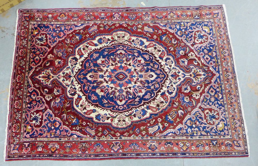 A large Persian carpet, the red filed with a central medallion and flower head border, 215 x 310cm