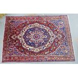 A large Persian carpet, the red filed with a central medallion and flower head border, 215 x 310cm