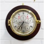 Sewills Sealord brass bulkhead clock with a silvered dial and brass case, on a wooden panel, overall