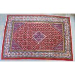 A large Eastern rug with red field and foliate pattern, flowerhead borders, 322 x 215cm