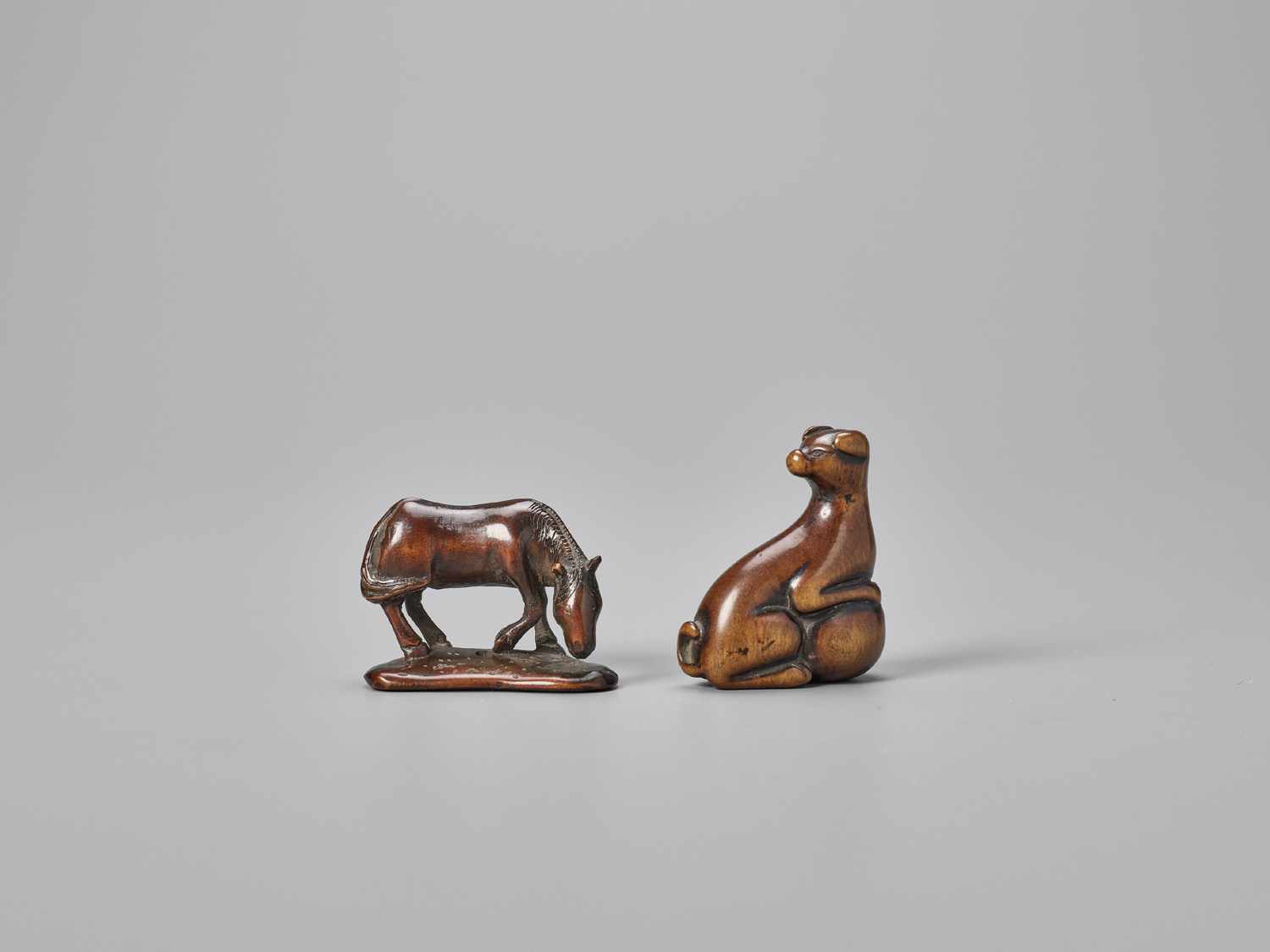 TWO WOOD NETSUKE OF A HORSE AND A DOG WITH BALL