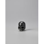 AN EBONY WOOD NETSUKE OF A SKULL